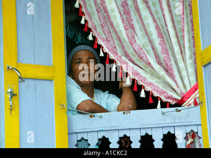 Woman in traditional house on stilts with shutters Malay village Pulau Pangkor island Malaysia Stock Photo