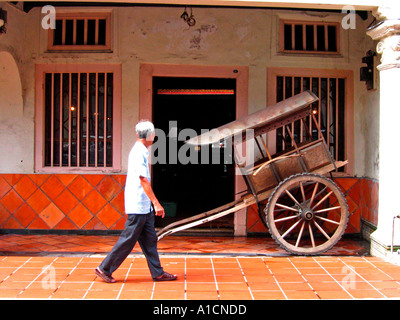 Man walks past rickshaw cart in house doorway Chinatown Malacca Malaysia Stock Photo