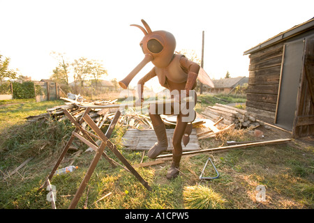 Man in mosquito costume sawing a wooden pole on a sunny autumn day Stock  Photo - Alamy