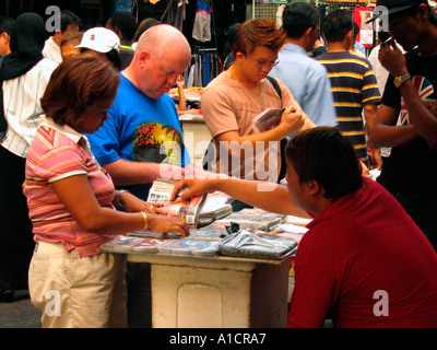 Browsing DVD sleeves in market just off Jalan Petaling Kuala Lumpur Stock Photo