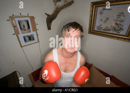 Middle-aged man happily posing with boxing gloves at home Stock Photo