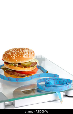 Hamburger and a measuring tape on bathroom scales Healthy Eating Dieting Junk food concept Stock Photo