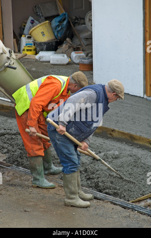 two construction workers spreading cement Stock Photo