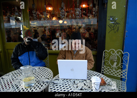 Hackney London December 2006 Broadway market La Bouche cafe and delicatessan Man using laptop outside Stock Photo