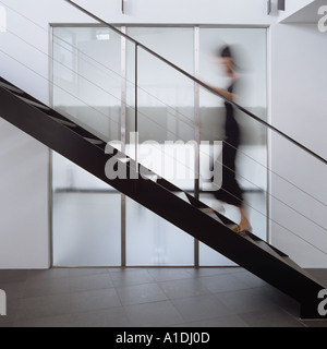 Blurred figure walking up modern metal staircase Stock Photo