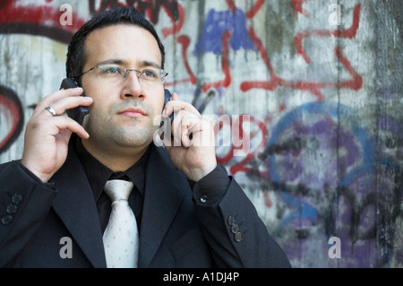 Businessman is calling in front of an graffiti wall Stock Photo