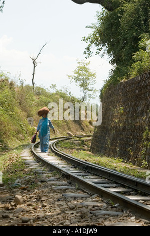 Indian woman in traditional dress carrying a pack on her head while walking along the scenic Shimla Kalka railway track in India. Stock Photo