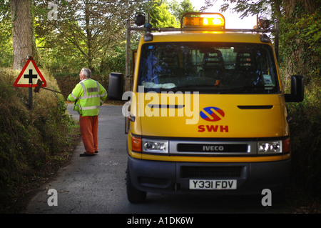 A HIGHWAYS WORKER CLEANING A CROSSROADS SIGN IN DEVON UK Stock Photo