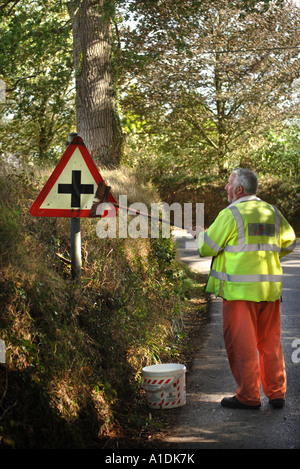 A HIGHWAYS WORKER CLEANING A CROSSROADS SIGN IN DEVON UK Stock Photo