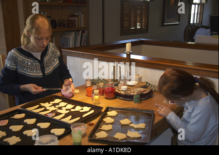 Girls decorating sugar cookies at kitchen table Stock Photo