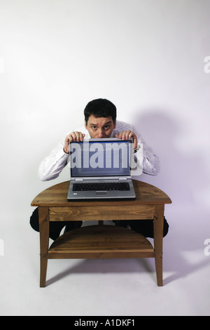 Business man hides behind his laptop with a pensive look Stock Photo