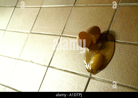Broken egg on ceramic tile floor Stock Photo