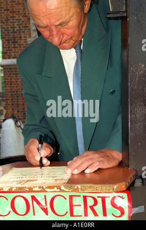 Old man in suit writing certificate of Hejnal Listening at Main Square Rynek Glowny, Cracow Krakow, Poland 2006 Stock Photo
