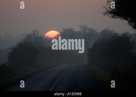 Winter sun sets over empty country road Swinbrook Oxfordshire UK Stock Photo