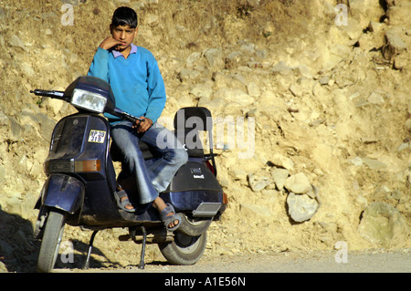 Young indian teenager dreaming about harley superbike sitting on his poor old scooter, McLeod Ganj, India Stock Photo