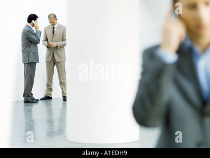 Businessmen in lobby using cell phones Stock Photo