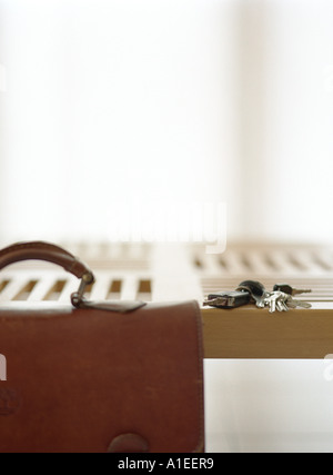 Briefcase and keys on table Stock Photo