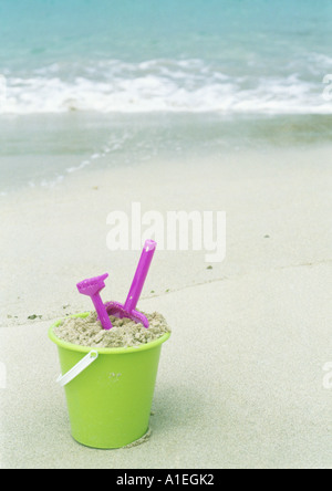 Bucket full and rake on the sand with copy space on a white background ...