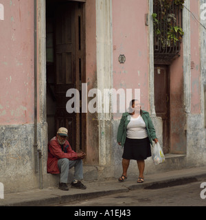 Man sitting in a doorway with a woman standing beside him Havana Cuba Stock Photo