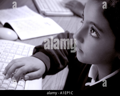 1990s computer Infant junior schoolgirl Hispanic pupil with bright eyes studying intently at computer screen in school computer classroom Black+White Stock Photo