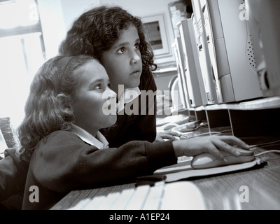Two junior schoolgirls work together on their computer terminal in modern spacious school computer classroom Stock Photo
