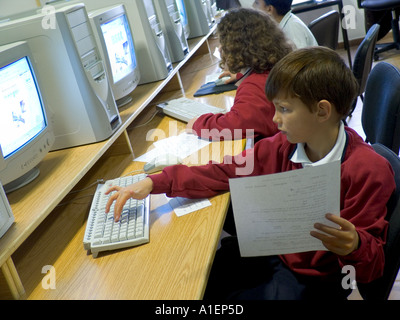 COMPUTER CLASS SCHOOL Junior schoolboy 7-9 years works on his computer terminal in modern light school computer classroom Stock Photo