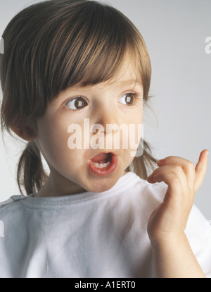 Surprised kid looking away, pointing finger on isolated studio ...