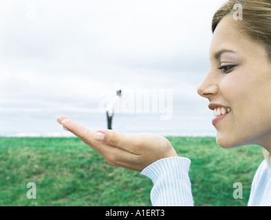 Man standing on woman's hand, optical illusion