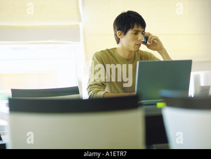 Man using laptop and phoning