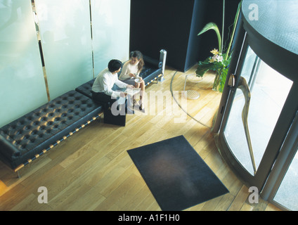 Man and woman sitting on bench in lobby, high angle view Stock Photo