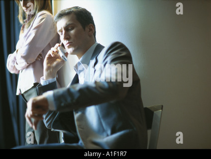 Businessman on phone, checking time, woman standing next to him Stock Photo