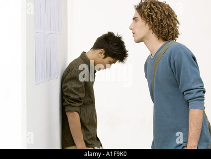 Two students standing near results posted on wall Stock Photo