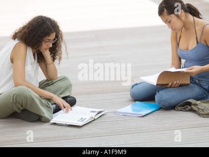 Two students sitting on ground, studying Stock Photo
