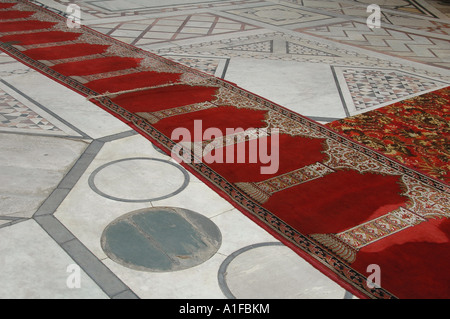 Long red rug on decorated white marble floor of Mosque Madrassa of Sultan Hassan located in Cairo Egypt