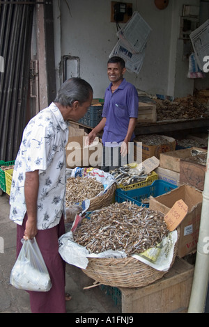 Customer inspecting fishmongers dried salted fish Kandy Sri Lanka Stock Photo