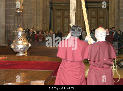 Two priests pulling up a smoking Botafumeiro in the Cathedral of Santiago de Compostela Stock Photo