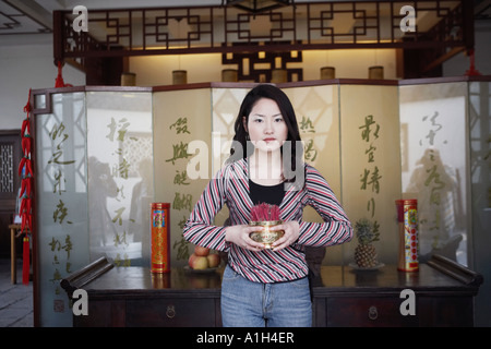 Portrait of a young woman holding a bowl of incense sticks Stock Photo