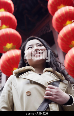 Close-up of a young woman standing in front of hanging Chinese lanterns Stock Photo