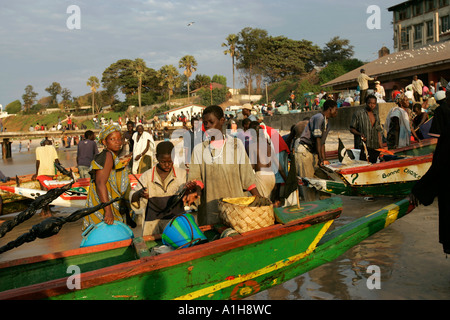 Fishing boats return to jetty at Bakau Fish market with catch The Gambia Stock Photo