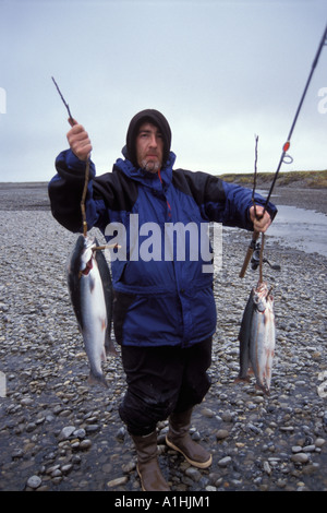 sport fisherman holds up catch of Arctic char Salvelinus alpinus along a river in the central Arctic North Slope Alaska Stock Photo