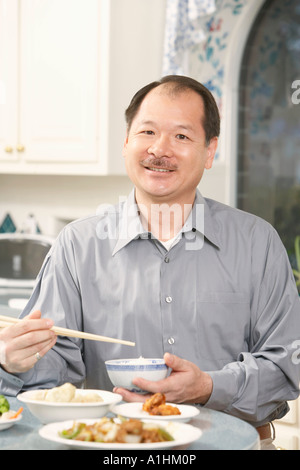 Portrait of a senior man holding a bowl with a pair of chopsticks Stock Photo