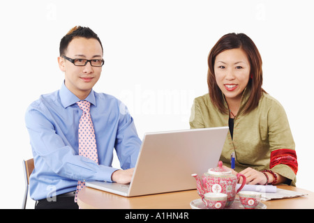 Portrait of a businessman and a businesswoman sitting in front of a laptop Stock Photo