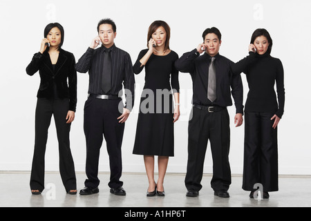 Portrait of three businesswomen and two businessmen using mobile phones Stock Photo
