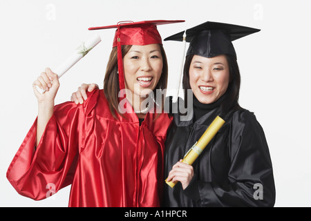 Portrait of two female graduates holding diplomas Stock Photo