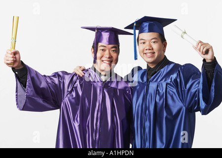 Portrait of two male graduates holding diplomas Stock Photo