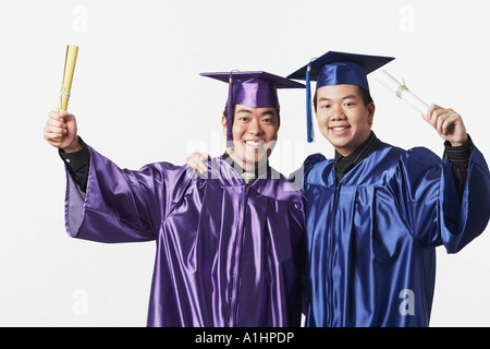 Portrait of two male graduates holding diplomas Stock Photo