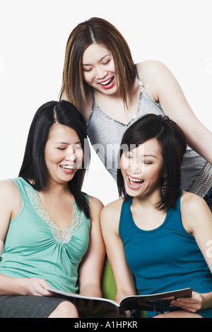 Close-up of three young women looking at a magazine Stock Photo