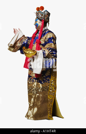 Side profile of a male Chinese opera performer holding a bowl full of gold coins Stock Photo