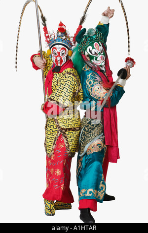 Side profile of two male Chinese opera performers gesturing with weapons Stock Photo