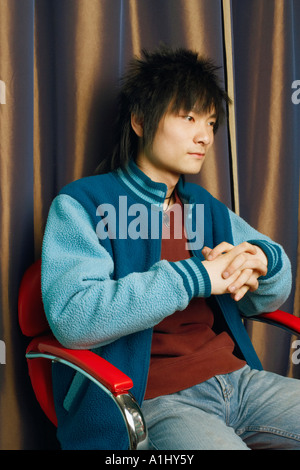 Close-up of a young man sitting on an armchair looking away Stock Photo